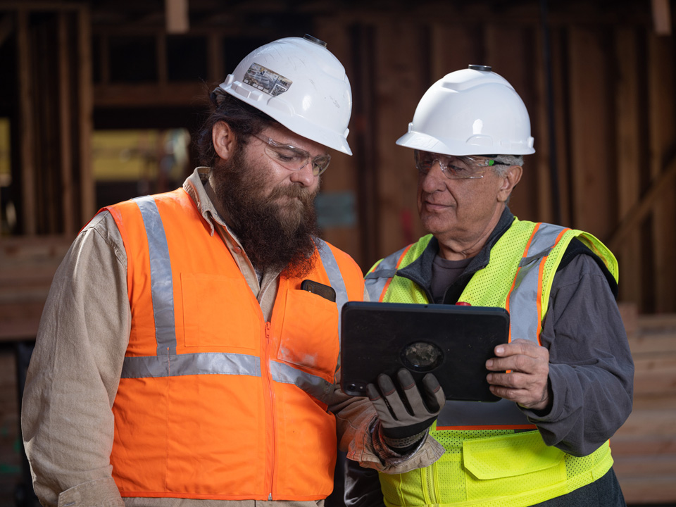 two construction workers looking at iPad